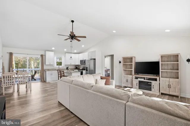 a kitchen with stainless steel appliances kitchen island granite countertop a stove a refrigerator a kitchen island a dining table and chairs with wooden floor