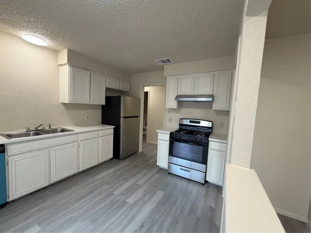 a kitchen with a refrigerator and a stove top oven