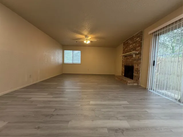 a view of an empty room with wooden floor and a fireplace