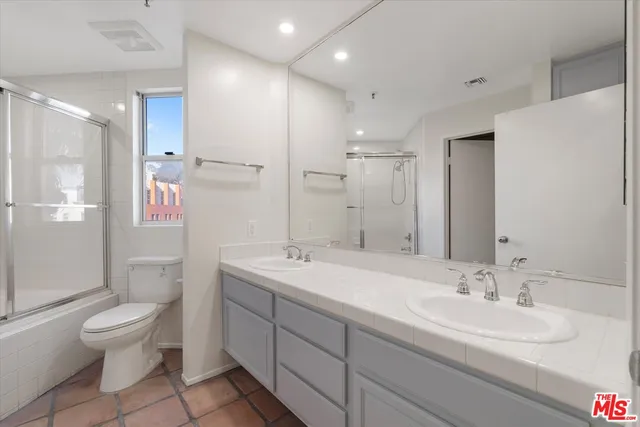 a spacious bathroom with a sink a toilet and a large mirror