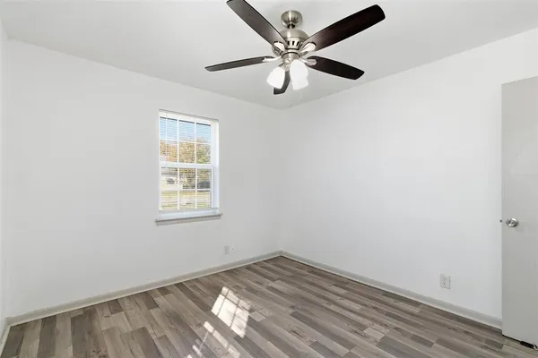 an empty room with a window and a ceiling fan