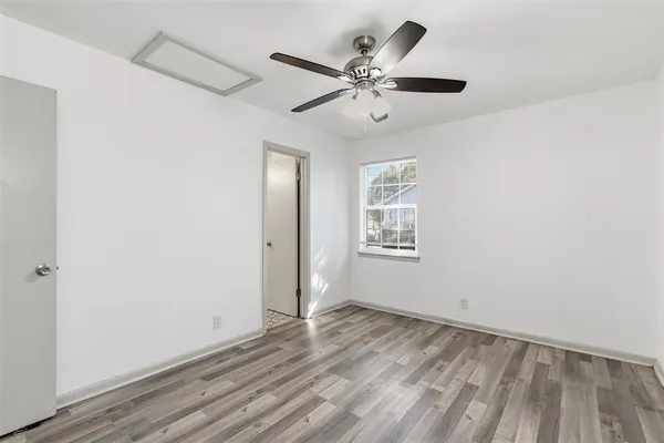 an empty room with wooden floor chandelier fan and windows