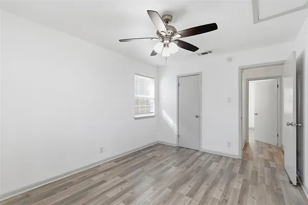 an empty room with wooden floor fan and windows