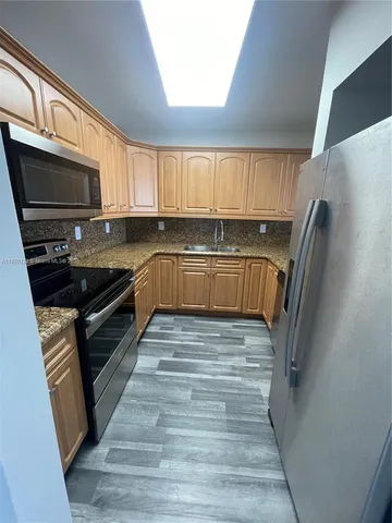 a kitchen with stainless steel appliances granite countertop a refrigerator a stove a sink and a microwave