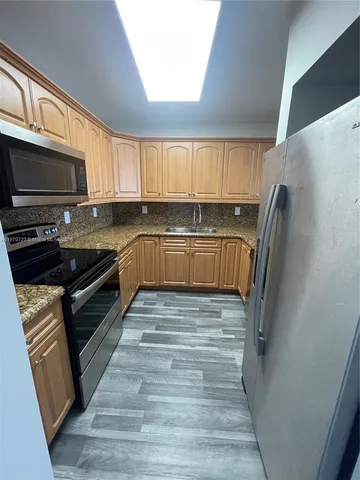 a kitchen with granite countertop a refrigerator stove top oven and sink