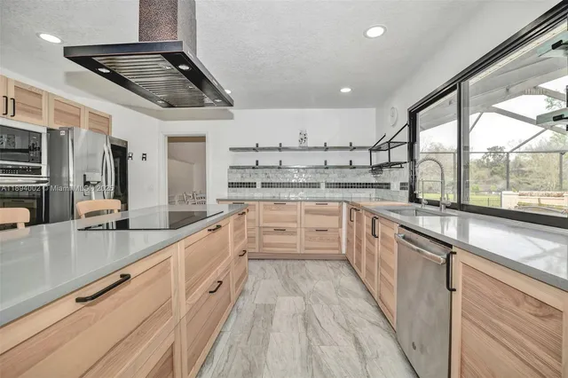 a large white kitchen with stainless steel appliances granite countertop a lot of counter space and wooden floors