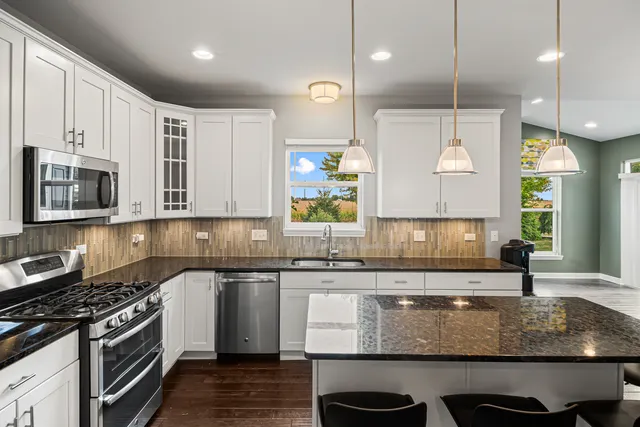 a kitchen with stainless steel appliances granite countertop a stove a sink and a microwave