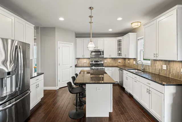 a kitchen with kitchen island a counter top space a sink stainless steel appliances and cabinets