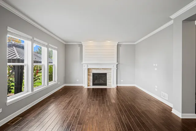 wooden floor fireplace and windows in an empty room