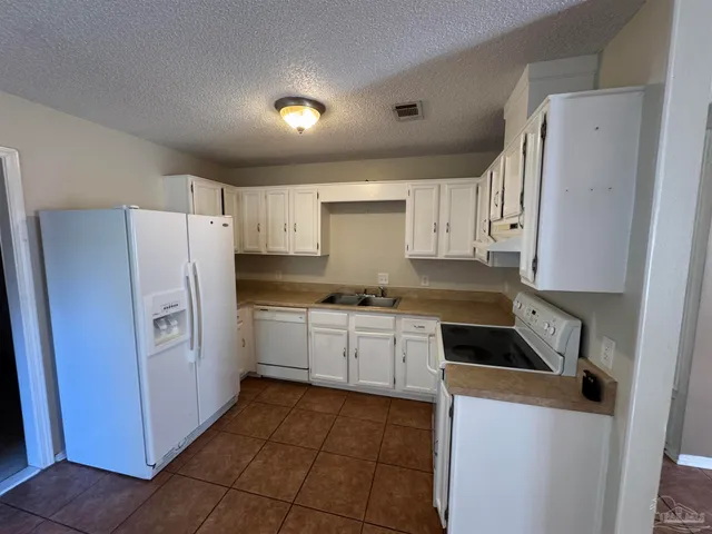 a kitchen with a refrigerator a sink and cabinets