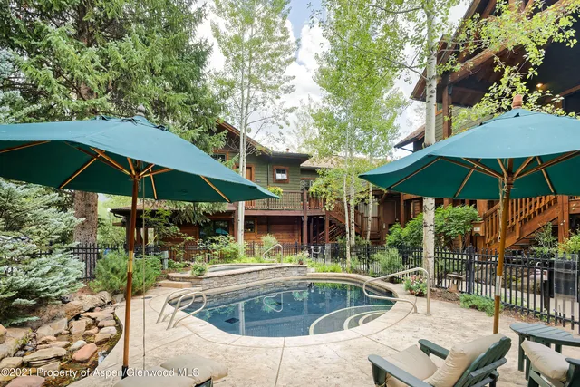 a view of pool with table and chairs under an umbrella