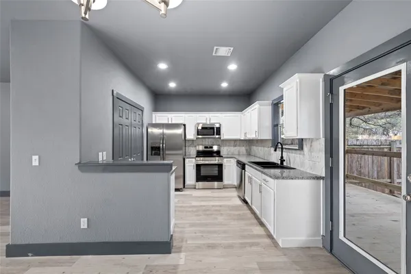 a kitchen with white cabinets and stainless steel appliances