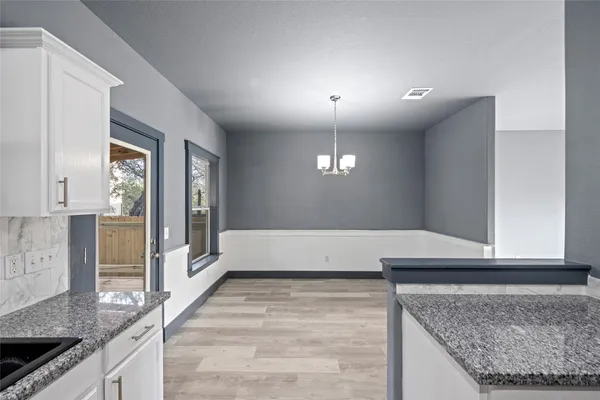 a large kitchen with stainless steel appliances granite countertop a sink dishwasher with a dining table and chairs with wooden floor