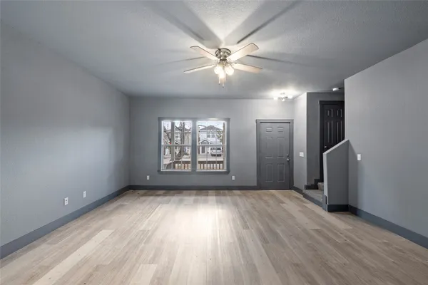 a view of an empty room with a window and wooden floor