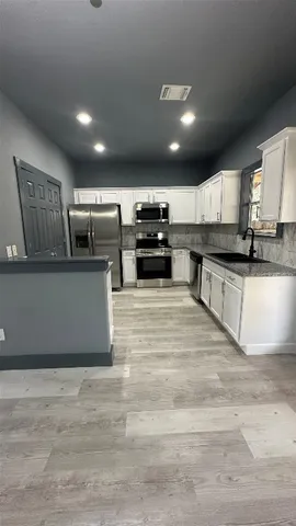 a large kitchen with stainless steel appliances kitchen island a large counter top and a wooden floor