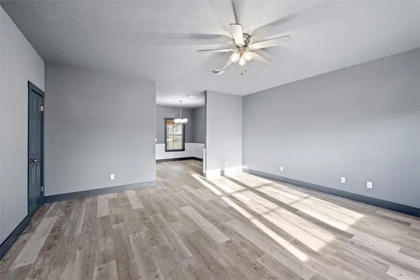 a view of an empty room with a window and a kitchen