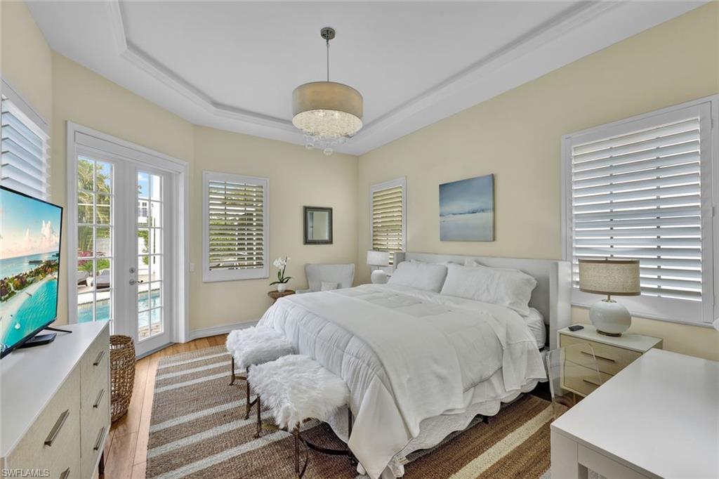 255 2nd Avenue North Naples, FL 34102 - Photo 13 of 32 a bedroom with a large bed and a flat tv screen on dresser