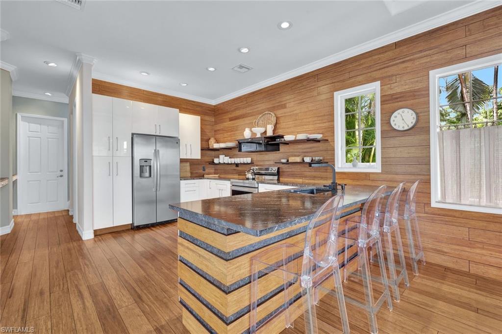 255 2nd Avenue North Naples, FL 34102 - Photo 6 of 32 a kitchen with stainless steel appliances granite countertop a refrigerator a sink a stove and white cabinets with wooden floor