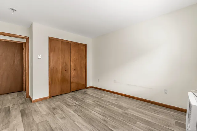 a view of an empty room with wooden floor and closet