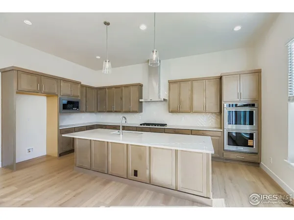 a kitchen with stainless steel appliances granite countertop a sink a stove a refrigerator and island with wooden floor
