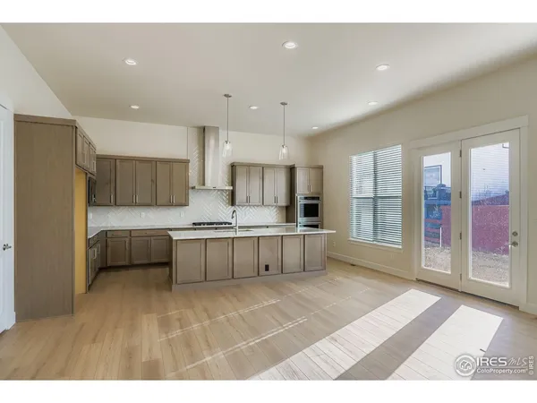 a large white kitchen with a large window and stainless steel appliances