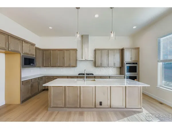 a kitchen with stainless steel appliances granite countertop a sink a microwave a refrigerator and white cabinets