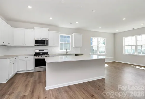 a large kitchen with cabinets wooden floor and stainless steel appliances