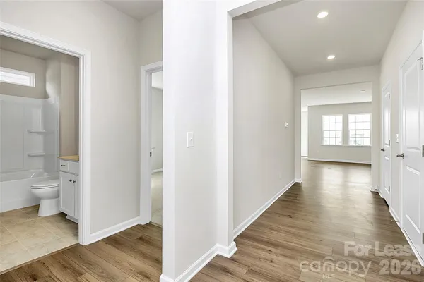 a view of a hallway with wooden floor and a bathroom