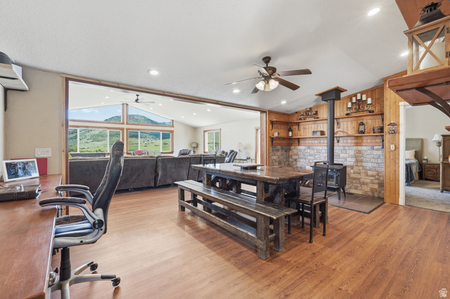 8066 North Valley View Heights Preston, ID 83263 - Photo 9 of 34 Spacious open-concept interior featuring wood-finish flooring, a freestanding wood-burning stove with a stone surround, and an integrated ceiling fan