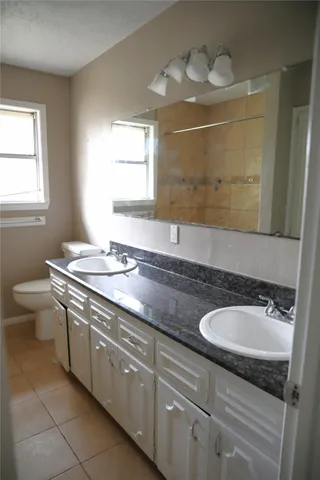 a bathroom with a granite countertop sink a toilet and a mirror