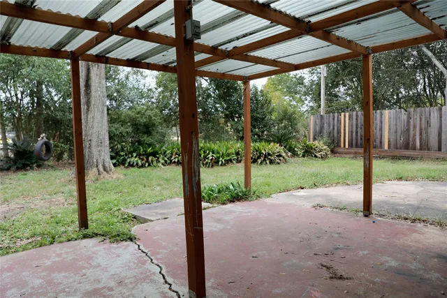 a view of a yard with porch and wooden fence