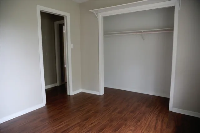 a view of an empty room with wooden floor and closet
