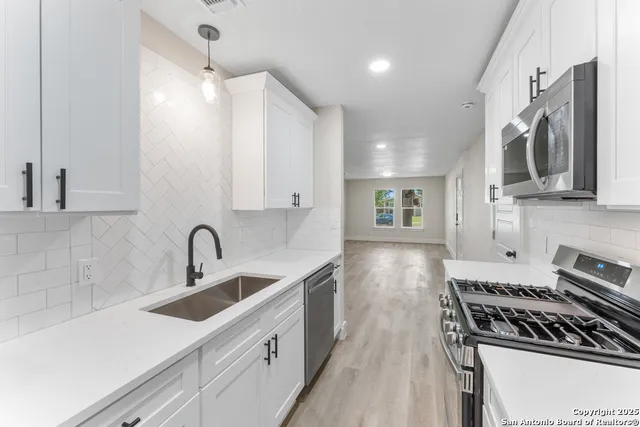 a kitchen with stainless steel appliances a sink stove and cabinets