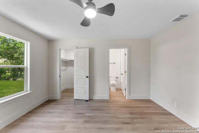 a view of an empty room with window and wooden floor
