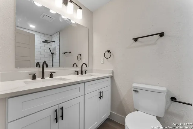 a bathroom with a toilet sink a mirror and vanity