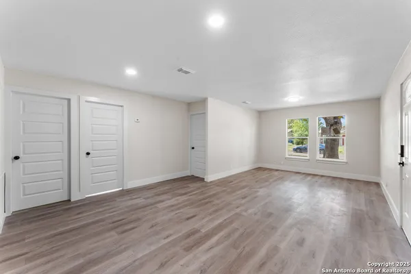 an empty room with wooden floor and windows