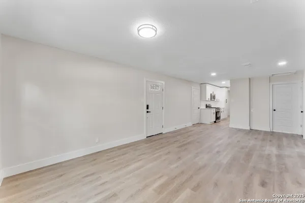 a view of empty room with kitchen and window
