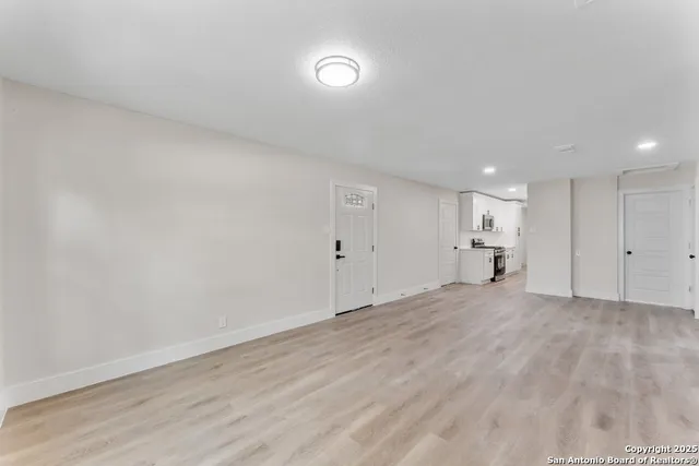 a view of empty room with kitchen and window