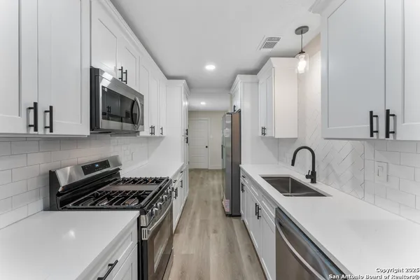 a kitchen with stainless steel appliances a sink a stove and microwave