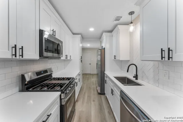 a kitchen with stainless steel appliances a sink a stove and microwave