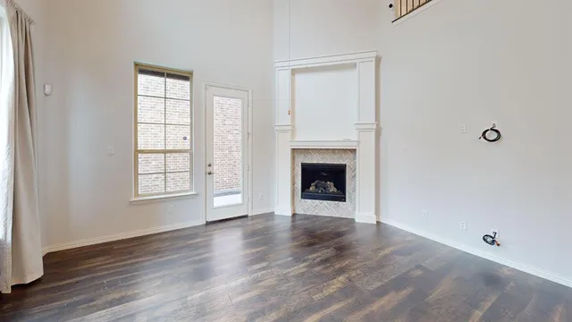 an empty room with wooden floor a fireplace and windows