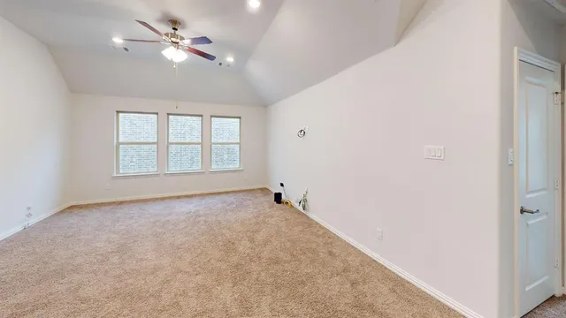 an empty room with chandelier fan and windows