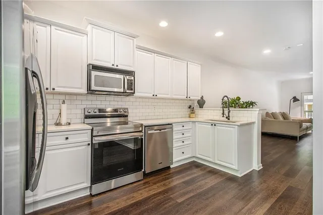 a kitchen with cabinets stainless steel appliances a sink and wooden floor
