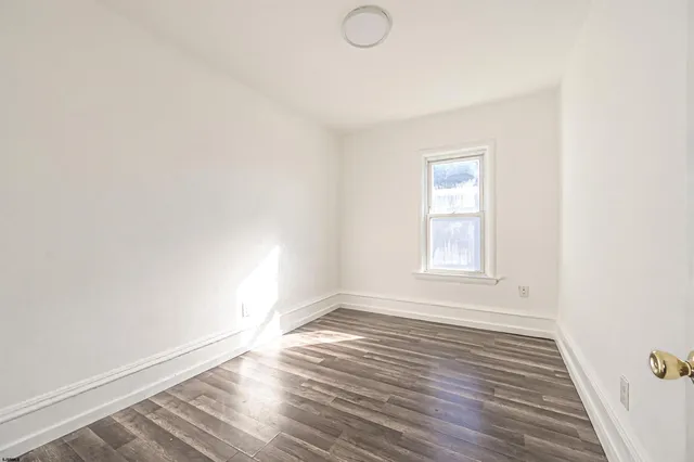 an empty room with wooden floor cabinet and windows