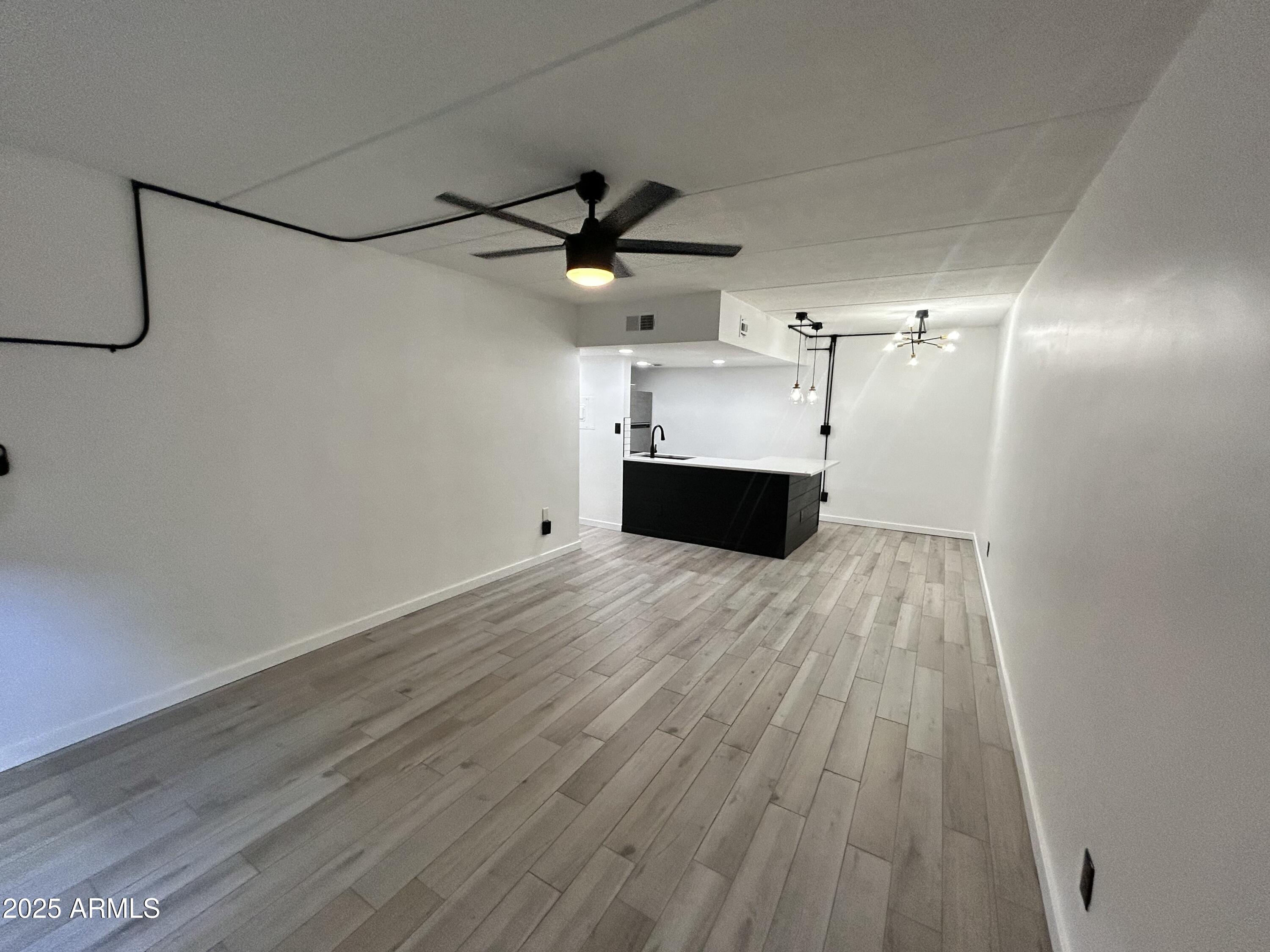 3416 North 44th Street, Unit 34 Phoenix, AZ 85018 - Photo 3 of 41 a view of empty room with wooden floor and ceiling fan