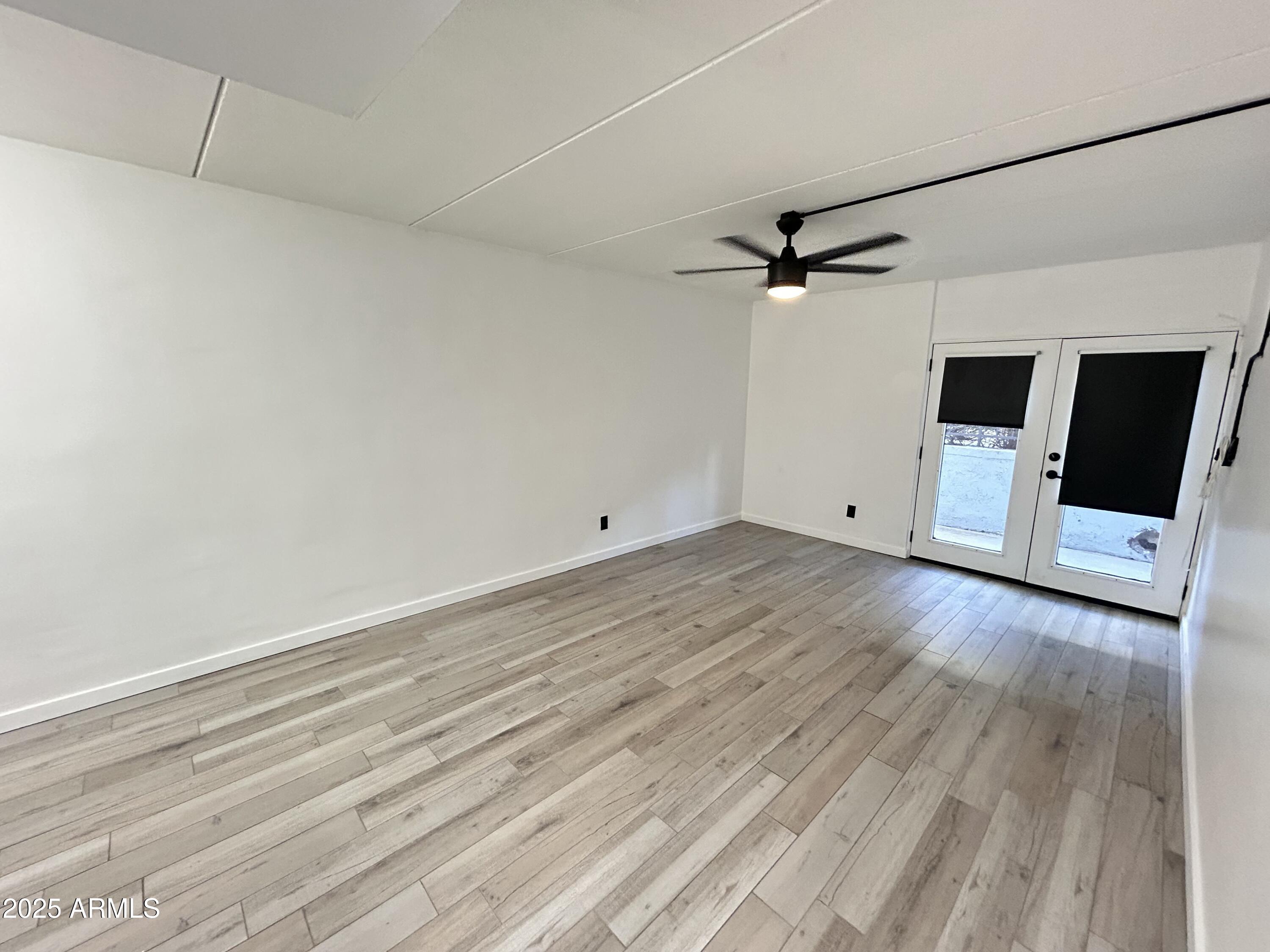 3416 North 44th Street, Unit 34 Phoenix, AZ 85018 - Photo 41 of 41 a view of an empty room with a ceiling fan and wooden floor