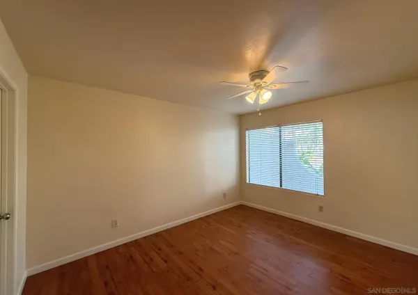 an empty room with wooden floor and fan