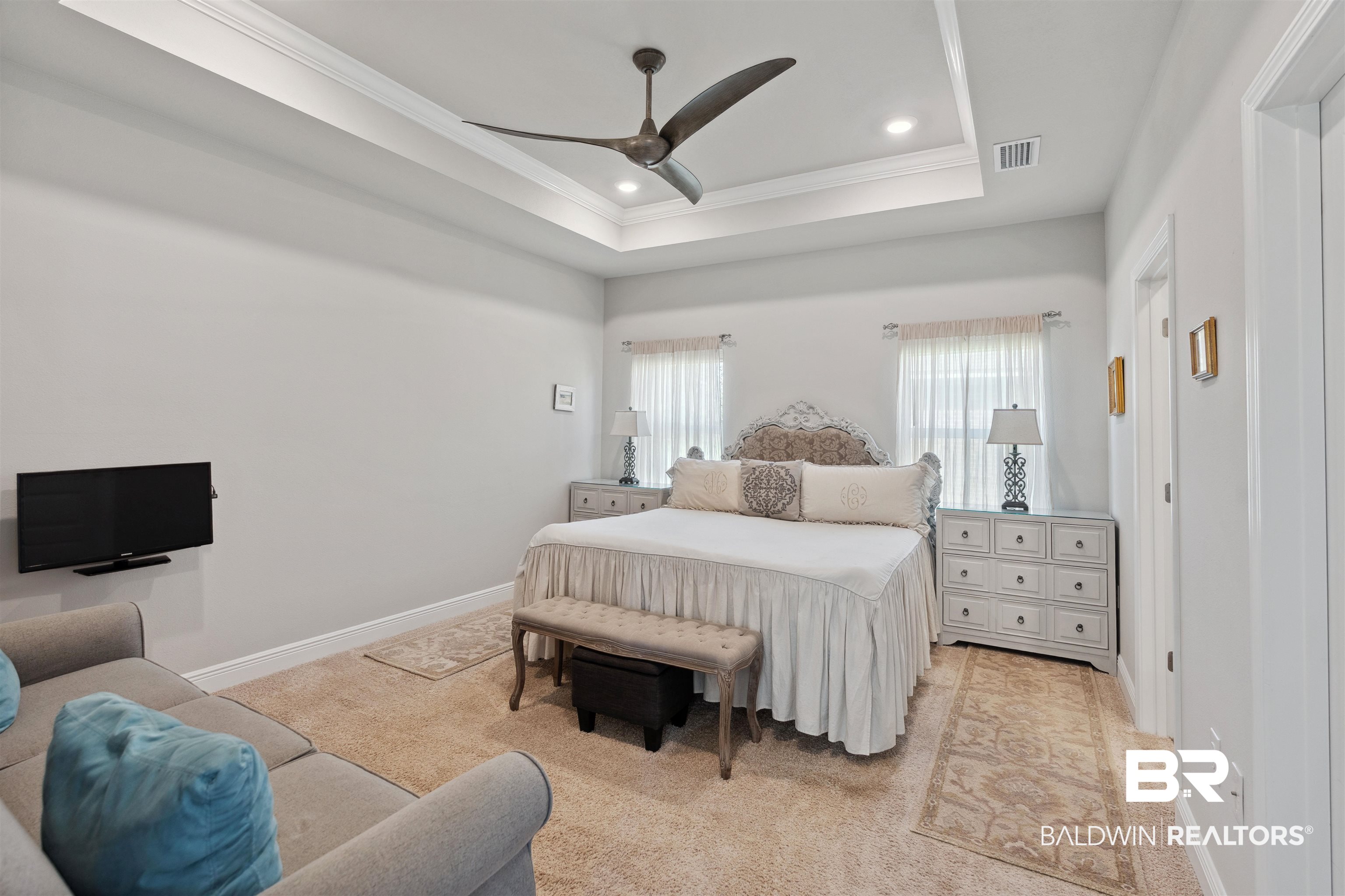 23809 Devonfield Lane Daphne, AL 36526 - Photo 16 of 29 Bedroom featuring visible vents, crown molding, baseboards, light carpet, and a tray ceiling