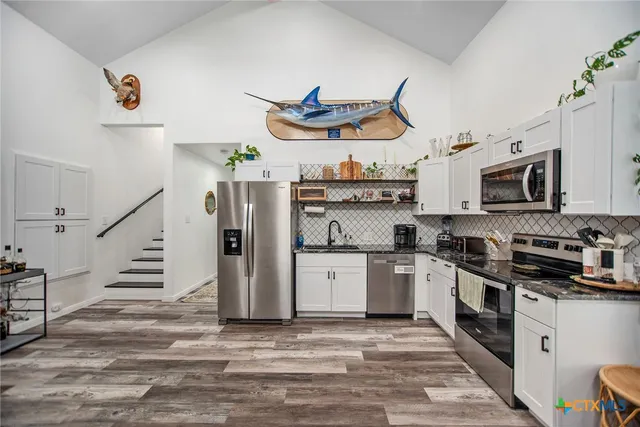 a kitchen with stainless steel appliances granite countertop a refrigerator and a stove top oven