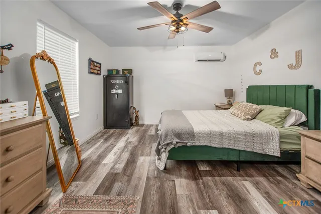 a bedroom with a bed a dresser with wooden floor
